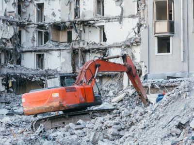 cleaning-construction-debris-with-bucket-excavator-ruins-building